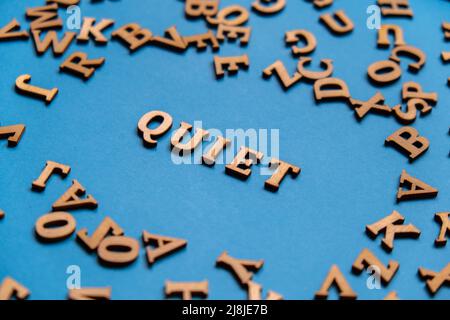 Parola TRANQUILLA fatta di lettere di legno su sfondo blu chiaro. Concetto di citazioni di parole motivazionali. Frase di ispirazione Foto Stock