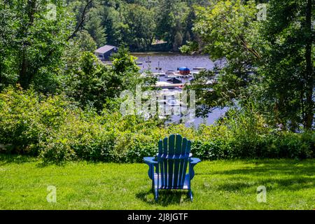 Sedia in legno in un parco verde che si affaccia sul lago Rosseau in Ontario, Canada Foto Stock