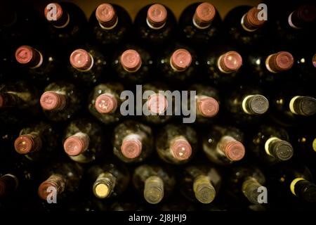 Mucchio di bottiglie di vino con tappi posti l'uno sull'altro in cantine durante l'invecchiamento Foto Stock