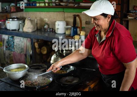 La donna sorride mentre cuoca la colazione tradizionale in Costa Rica. Foto Stock