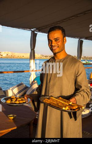 Membro dell'equipaggio che serve la colazione al mattino presto su una barca sul Nilo Dahabiya Foto Stock