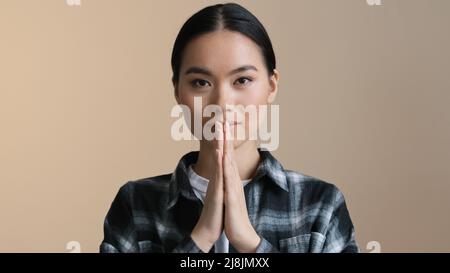 Primo piano ritratto asiatico calma ragazza piega palme di fronte archi namaste saluto preghiera. Donna coreana giapponese donna cinese che chiede perdono scuse Foto Stock