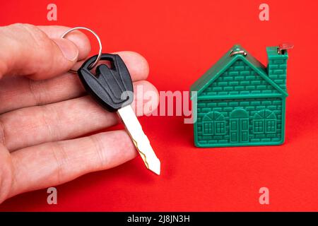 mano dell'uomo che tiene la chiave alla casa, e un modello della casa Foto Stock