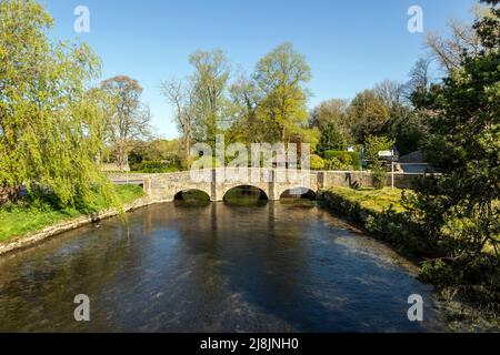 Vecchio ponte di pietra sul fiume Coln, che scorre attraverso il villaggio Cotswolds di Bibury, Gloucestershire, Inghilterra, Regno Unito. Foto Stock