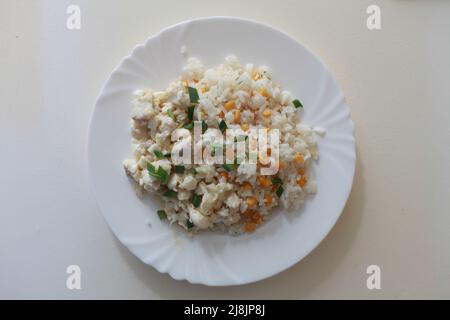 piatto con riso, cipolle verdi, mais e pesce su un piatto in alto shot Foto Stock