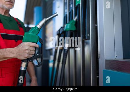 Lavoratore senior in piedi sulla stazione di servizio e auto di rifornimento. Foto Stock