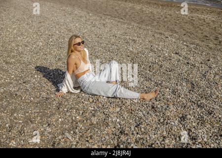 Signora gioiosa che si rilassa su una spiaggia vuota durante le vacanze estive Foto Stock