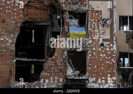 La bandiera Ucraina è visibile su una finestra di una casa distrutta che è stata danneggiata a causa dell'abbattimento dell'esercito russo nella città di Irpin, vicino alla capitale Ucraina Kiev. La Russia ha invaso l'Ucraina il 24 febbraio 2022, scatenando il più grande attacco militare in Europa dalla seconda guerra mondiale Foto Stock