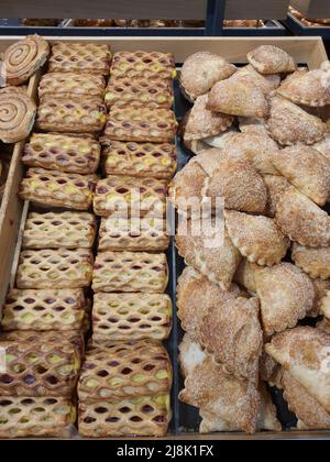 Pasta frolla surgelata dolce appena sfornata con marmellata, budino alla vaniglia e formaggio cremoso in panetteria. Dolci freschi in tasca, dessert o snack pomeridiano presso il negozio di alimentari Foto Stock