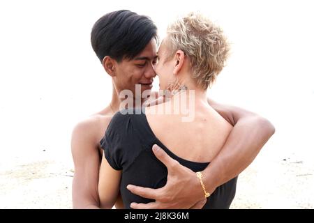 Coppia che guarda teneramente l'uno all'altro mentre abbraccia una spiaggia al tramonto Foto Stock