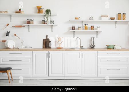 Interno di cucina luminosa con banconi bianchi e utensili Foto Stock