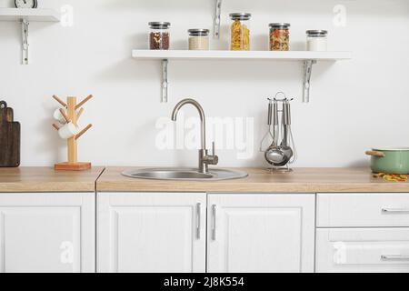 Interno di cucina luminosa con banconi bianchi e utensili Foto Stock