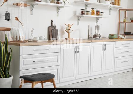 Interno di cucina luminosa con banconi bianchi e utensili Foto Stock