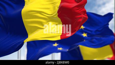 Dettaglio della bandiera nazionale della Romania che sventola nel vento con la bandiera dell'Unione europea sfocata sullo sfondo in una giornata chiara. Democrazia e politica. E Foto Stock