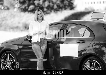 Happy Woman Instructor in prestito sulla sua auto - presumibilmente ha una pausa dalla guida Foto Stock