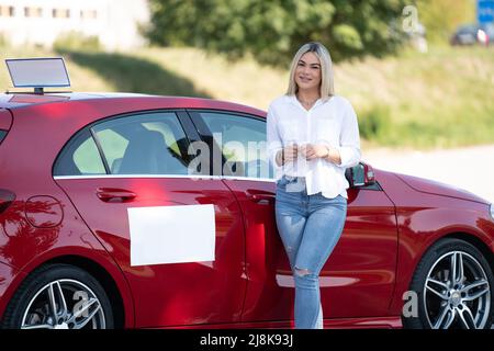 Happy Woman Instructor in prestito sulla sua auto - presumibilmente ha una pausa dalla guida Foto Stock