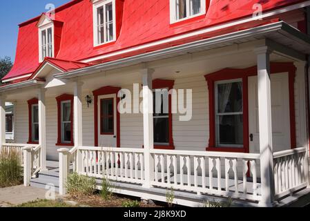 Vecchio circa 1825 Canadiana casa in stile cottage con legno bianco tegame e rosso lamiera mansarda tetto in estate. Foto Stock