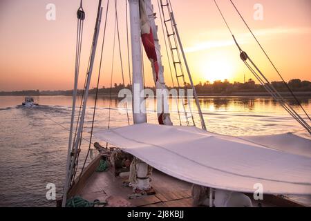 Crociera sul Nilo al tramonto in una barca turistica Nilo Dahabiya con una piccola barca rimorchiatore che tira la barca Foto Stock