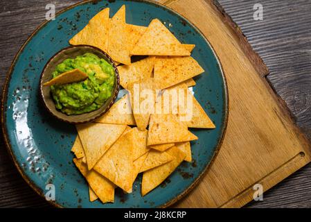 Piatto di nachos chips con salsa guacamole. Utensili fatti a mano. Innaffiatura in bocca. Cibo per feste. Foto Stock