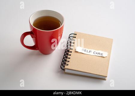 Cura di sé, testo su un pezzo di carta, sulla parte superiore di un blocco note accanto a una tazza di caffè. Cura di sé o concetto di amore te stesso. Foto Stock