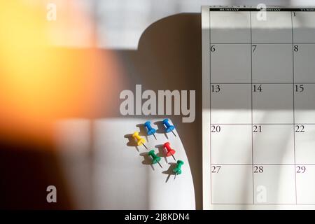 Thumbtack accanto al calendario, con ombra. Vista dall'alto. Pianificazione di riunioni e appuntamenti. Foto Stock