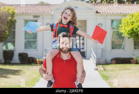 American padre e figlio camminando attraverso il parco della scuola. Primo giorno di autunno. Foto Stock