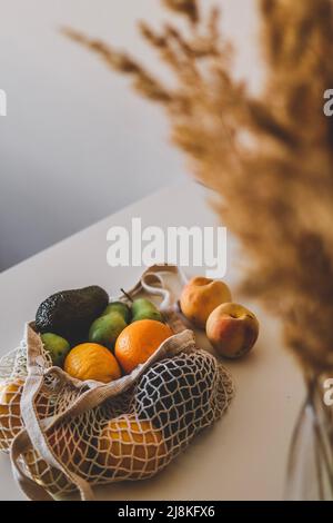 Una varietà di frutta in una borsa eco-aware si trovano sul tavolo. Superficie piana sana con spazio per la copia. Avocado, limoni, pesche, pere, arance. Foto Stock