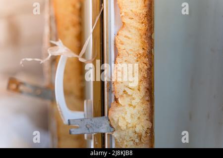 Un taglio della vecchia schiuma poliuretanica su una finestra in plastica smontata. Profilo in vetro isolante Foto Stock