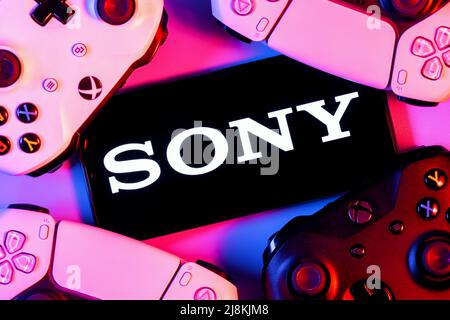 Smartphone con logo SONY sullo schermo circondato da gamepad. Foto Stock