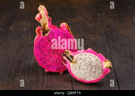 Due frutti di drago tagliati a metà su un tavolo di legno Foto Stock