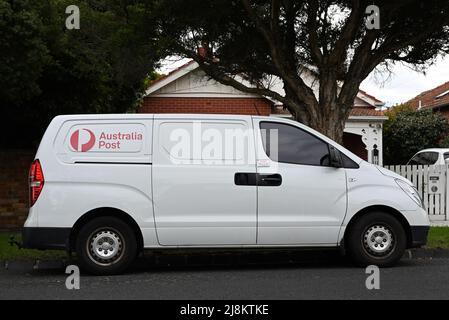 Vista laterale di un furgone Australia Post Delivery, un Hyundai Iload, si fermò su una strada suburbana, con una casa sullo sfondo Foto Stock