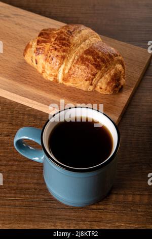 Tazza di caffè e croissant su sfondo di legno Foto Stock
