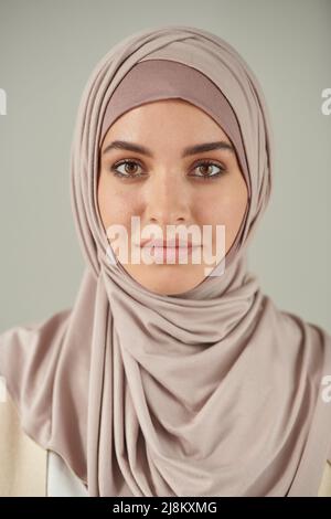 Verticale testa e spalle ritratto di bella giovane donna che indossa rosa pallido hijab guardando la macchina fotografica Foto Stock