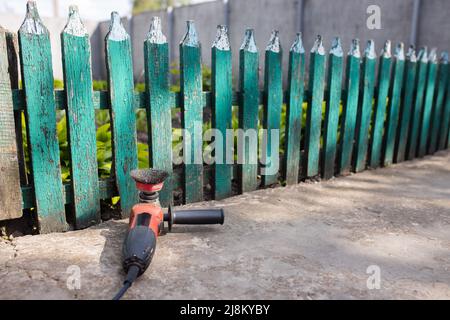 Lo strumento di pulizia della recinzione si trova sullo sfondo di una vecchia recinzione in legno. Foto di alta qualità Foto Stock