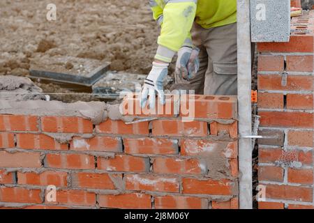 Muratore che posa mattoni su mortaio su nuova costruzione di casa residenziale. Ottieni NVQ in muratura Foto Stock