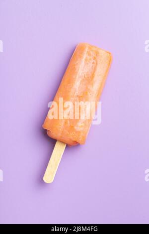 Ghiacciato fruttato. Dolce pop cicle su sfondo viola. Vista dall'alto. Foto Stock