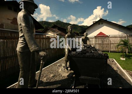 Sculture raffiguranti un supervisore che presta attenzione ai lavoratori che trasportano carbone da un carro ferroviario a Sawahlunto, un'ex città mineraria del carbone fondata dai colonialisti olandesi alla fine del 19th secolo a Sumatra occidentale, Indonesia. Foto Stock