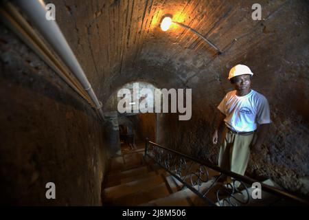 Ritratto di Wilizon, una guida, mentre è in piedi sulle scale che conducono giù al tunnel sotterraneo di estrazione del carbone a Sawahlunto, un'ex città mineraria del carbone fondata dai colonialisti olandesi alla fine del 19th secolo a Sumatra Occidentale, Indonesia. Foto Stock