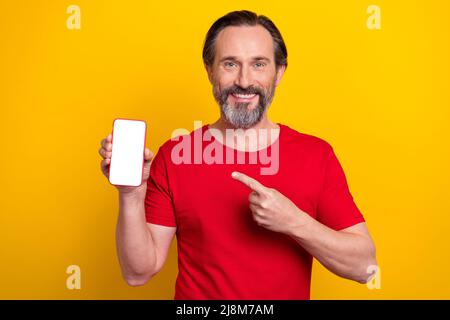 Foto di divertente giovane brunetta uomo inicato telefono indossare t-shirt rosso isolato su sfondo giallo Foto Stock