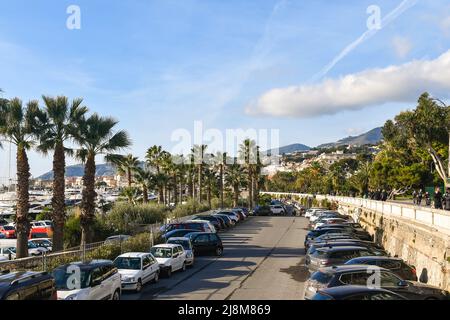 Il lungomare con il parcheggio del porto turistico (Portosole), circondato da palme e gente a piedi e in bicicletta sulla pista ciclabile, Sanremo Foto Stock