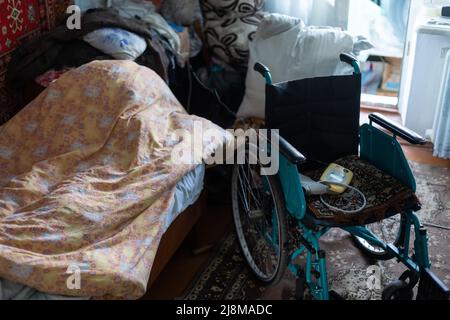 sedia a rotelle vuota in una vecchia casa molto povera Foto Stock