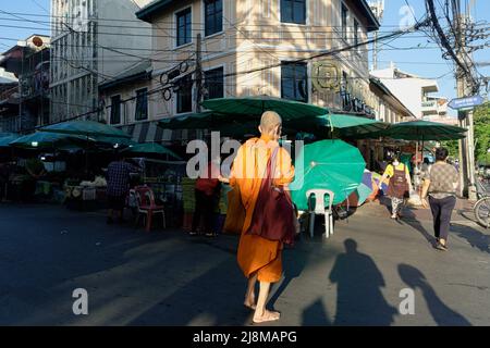 Alla luce del mattino presto, un monaco buddista cammina per una strada a Pak Klong Talat (mercato) a Bangkok, in Thailandia, portando una borsa piena di elemosine raccolte (cibo) Foto Stock