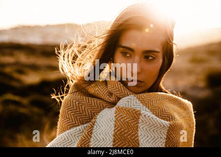 Bella giovane donna che cammina su un sentiero di legno avvolto con un tovagliolo di lana giallo Foto Stock