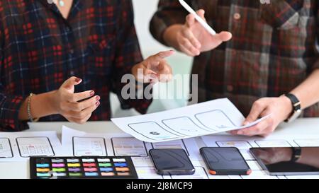 Immagine ritagliata di progettisti che creano prototipi di applicazioni mobili alla scrivania dell'ufficio. Foto Stock