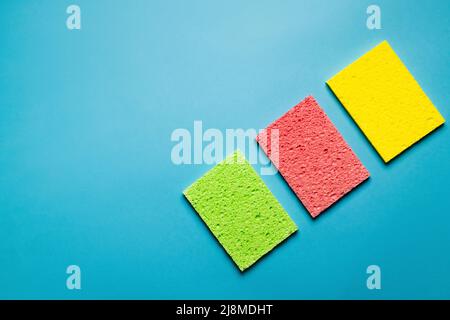 vista dall'alto degli stracci assorbenti verdi, rosa e gialli su sfondo blu Foto Stock