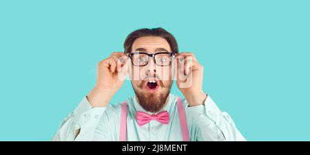 Uomo nerdy in occhiali, camicia e bow tie guardando la fotocamera con divertente sorpresa volto espressione Foto Stock
