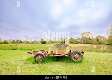 Un vecchio veicolo seduto in un campo verde Foto Stock