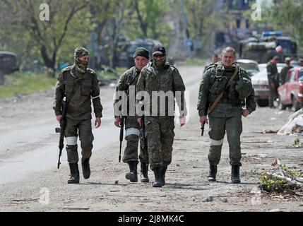 I membri di servizio delle truppe pro-russe camminano lungo una strada nella città portuale meridionale di Mariupol, Ucraina 17 maggio 2022. REUTERS/Alexander Ermochenko