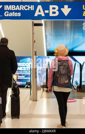 Donna con zaino e cappello di paglia che si avvicina al cancello d'imbarco al terminal di partenza dell'aeroporto Foto Stock