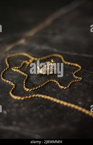 Anello d'oro a forma di coccodrillo con catena d'oro su sfondo di marmo scuro Foto Stock